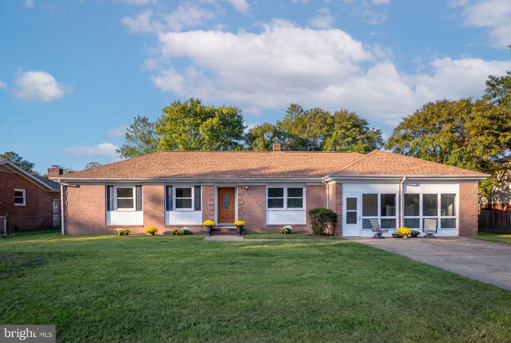 Single-story brick house with an enclosed sunroom, front lawn, and driveway.