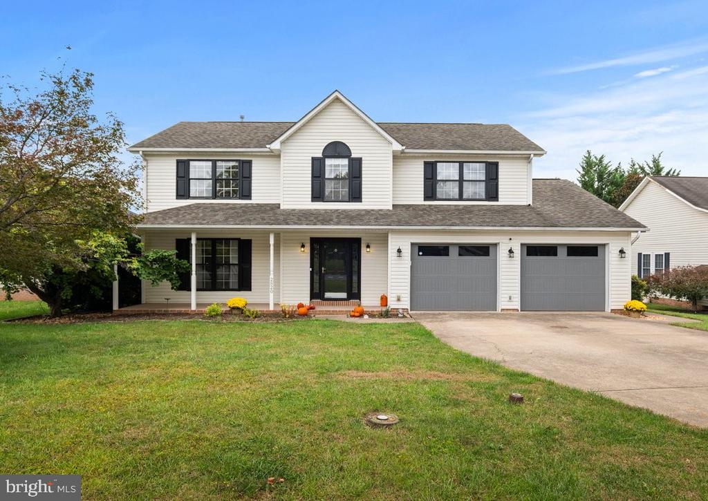 Two-story white house with black shutters, a covered porch, and a two-car garage.