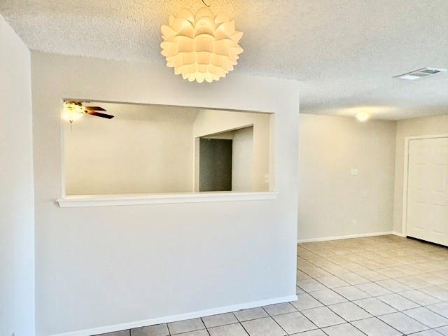 Empty tiled room with a wide pass-through opening and a white doorway.