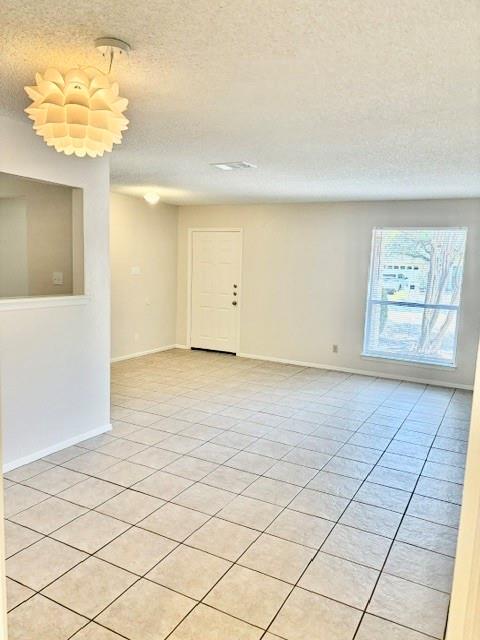 Vacant tiled room with a white entry door, window with blinds, and sculptural pendant light.