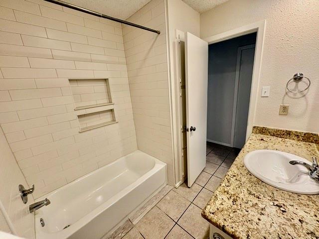 Bathroom with a tiled tub and recessed shelves beside a granite vanity and open doorway.