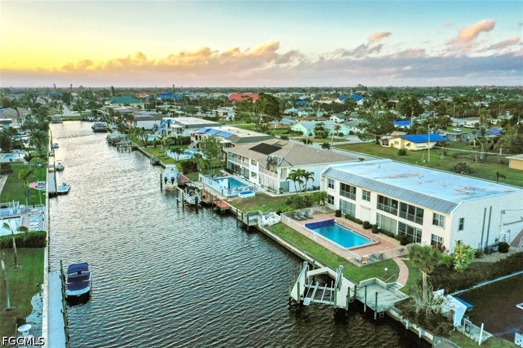Aerial view of canal-front condos with private docks and pools at golden hour.