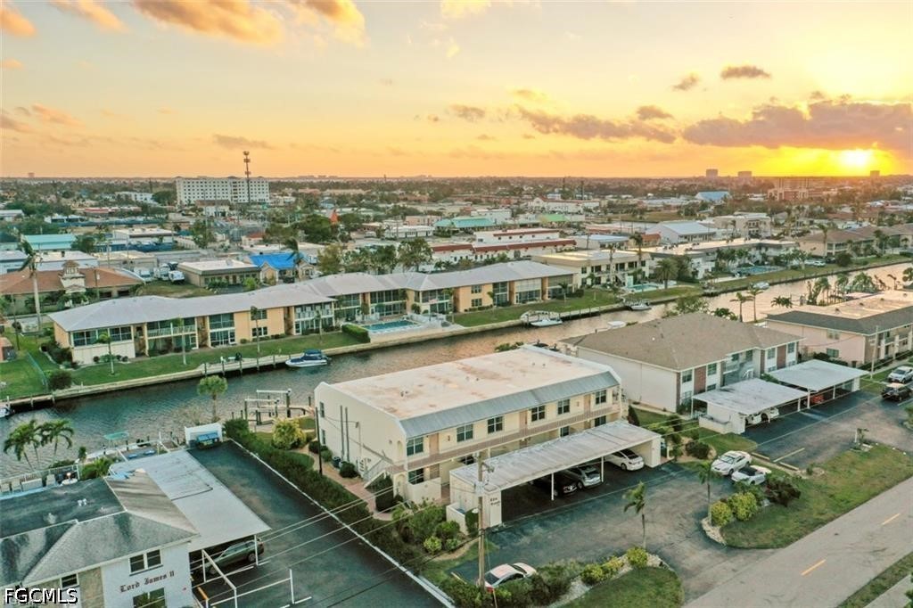 Aerial view of canal-side condos at sunset, with boats and the Cape Coral neighborhood beyond.