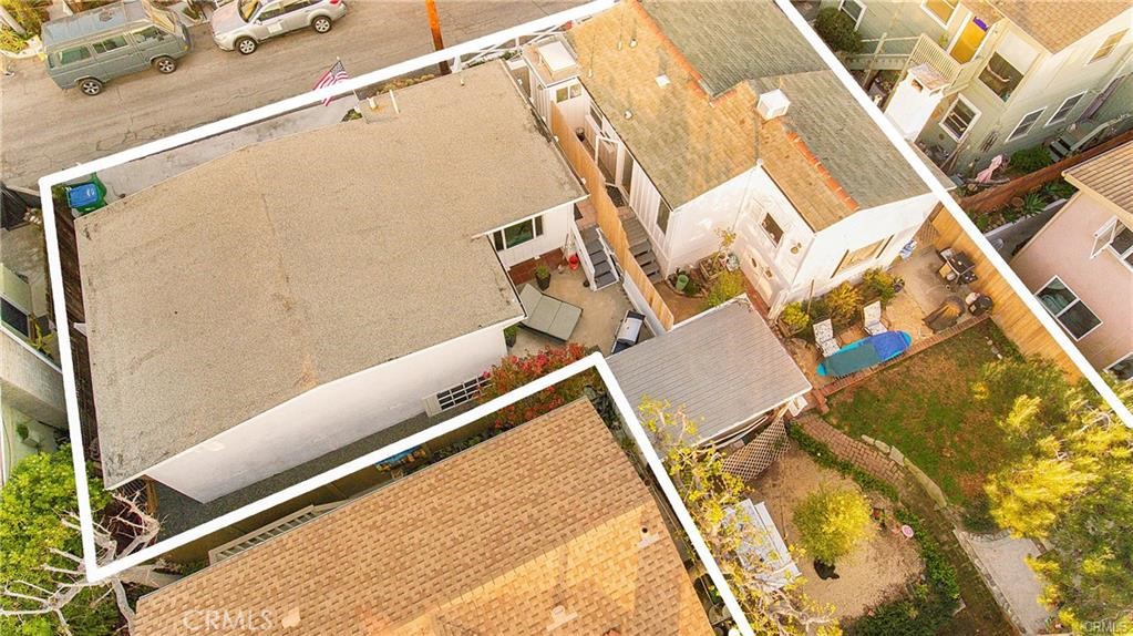 Aerial view of a house and its marked property boundary amid neighboring homes and yards.