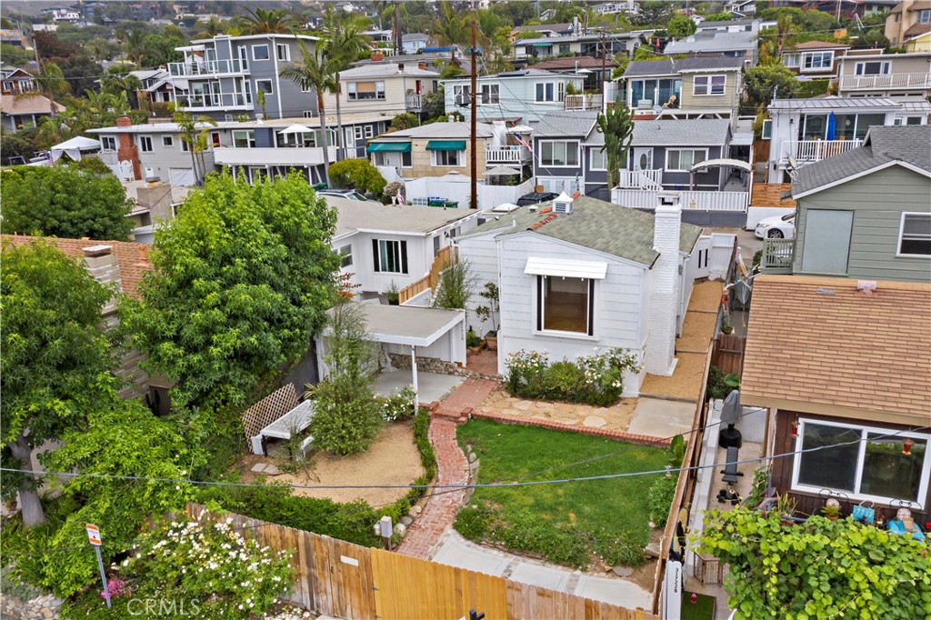 Elevated view of a white house with a brick garden path, lawn, and covered patio.