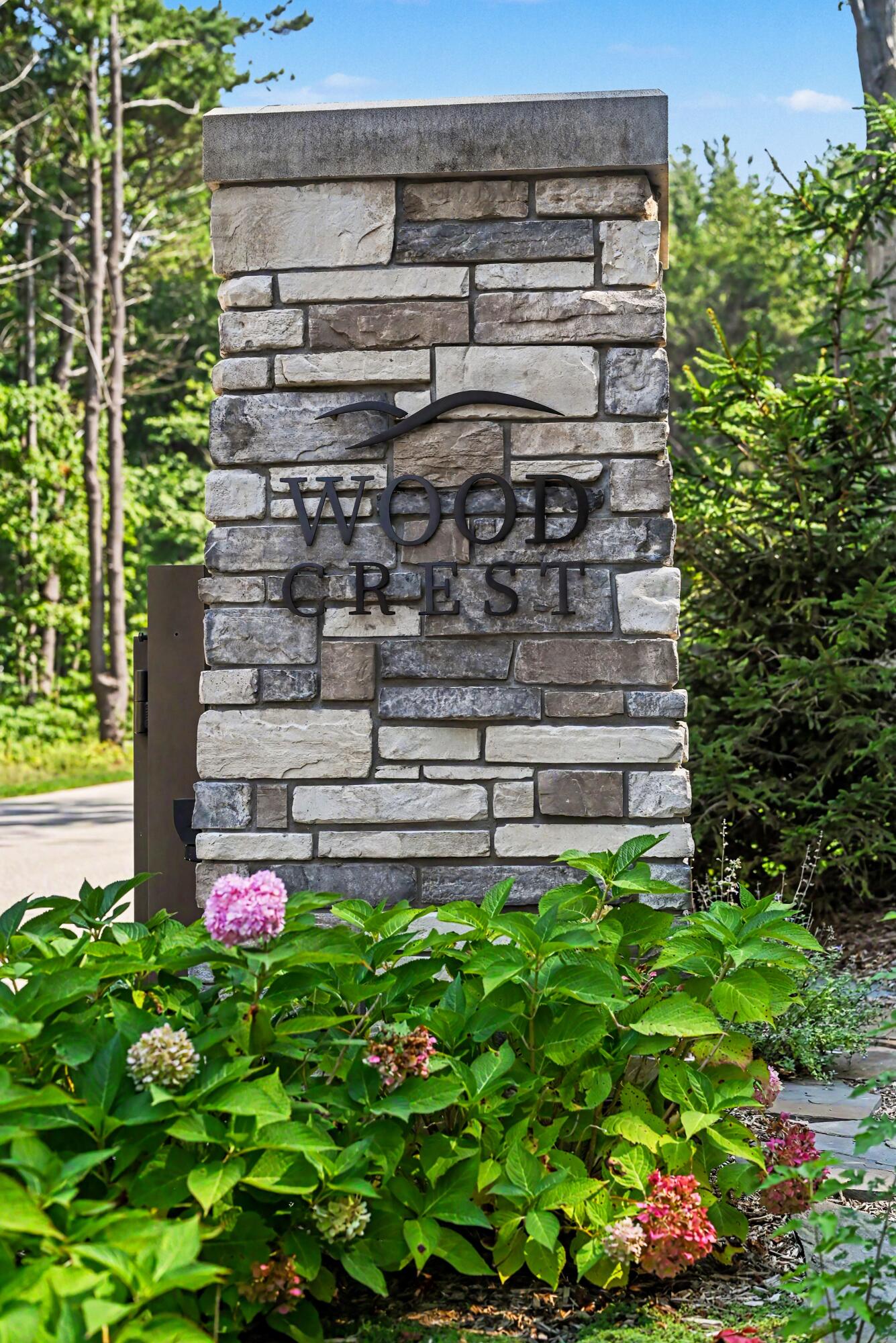 Wood Crest entrance sign among flowering hydrangeas and greenery.