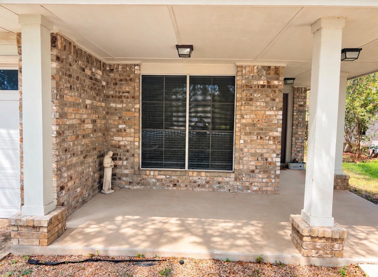 Brick home’s covered front porch with white columns and a large window.