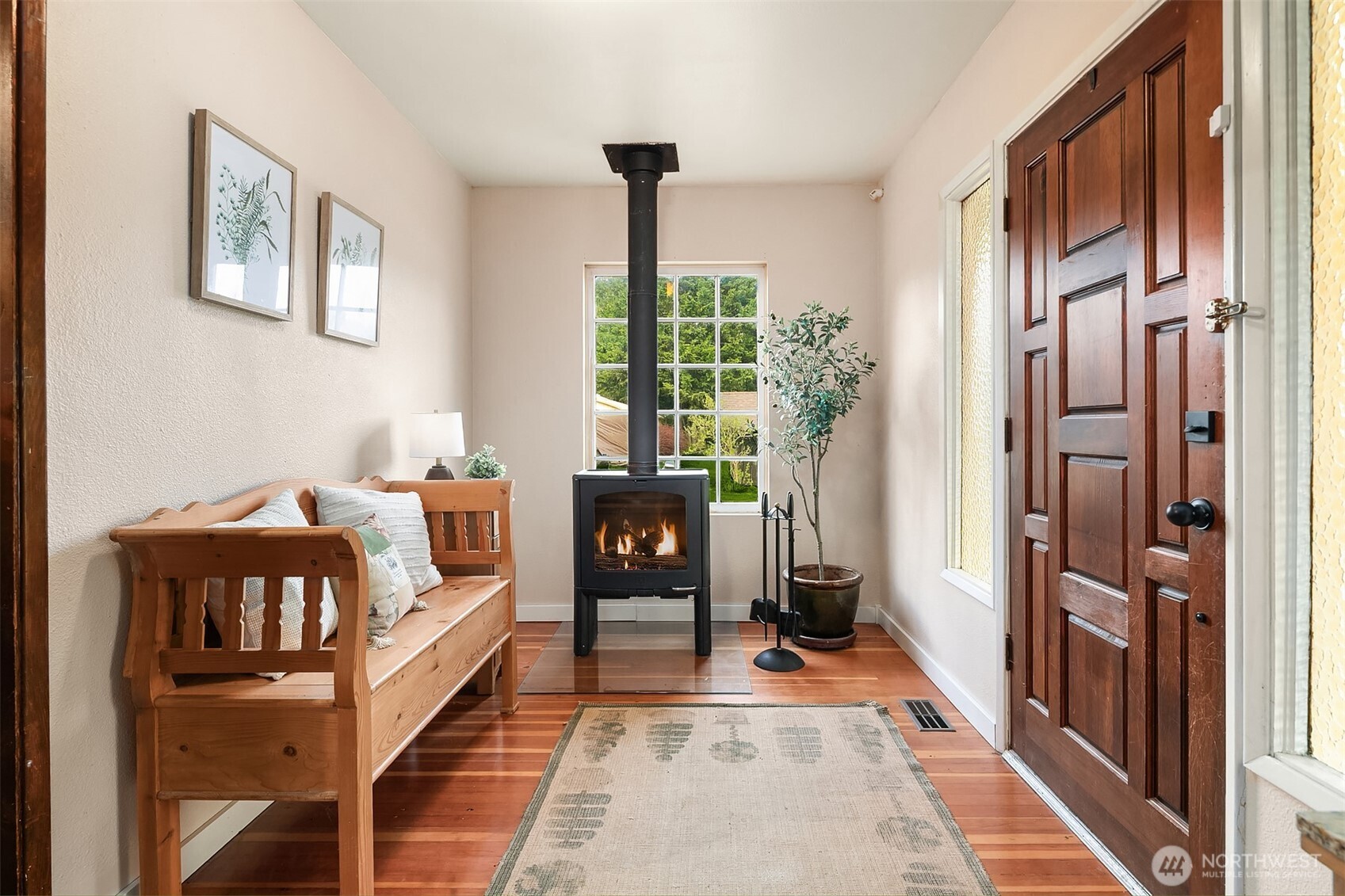 Furnished entryway with a wooden bench and lit wood stove beside the front door.