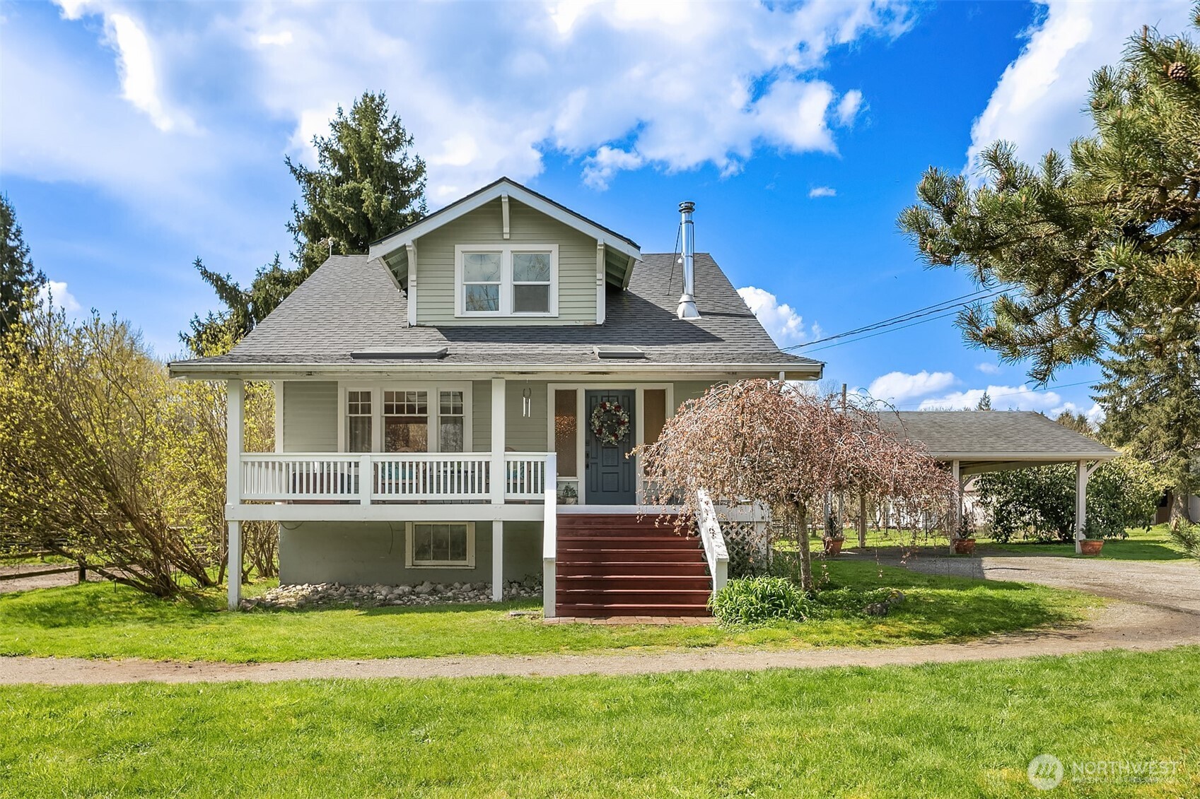 Light green two-story house with a broad porch, red entry steps, and an attached carport.