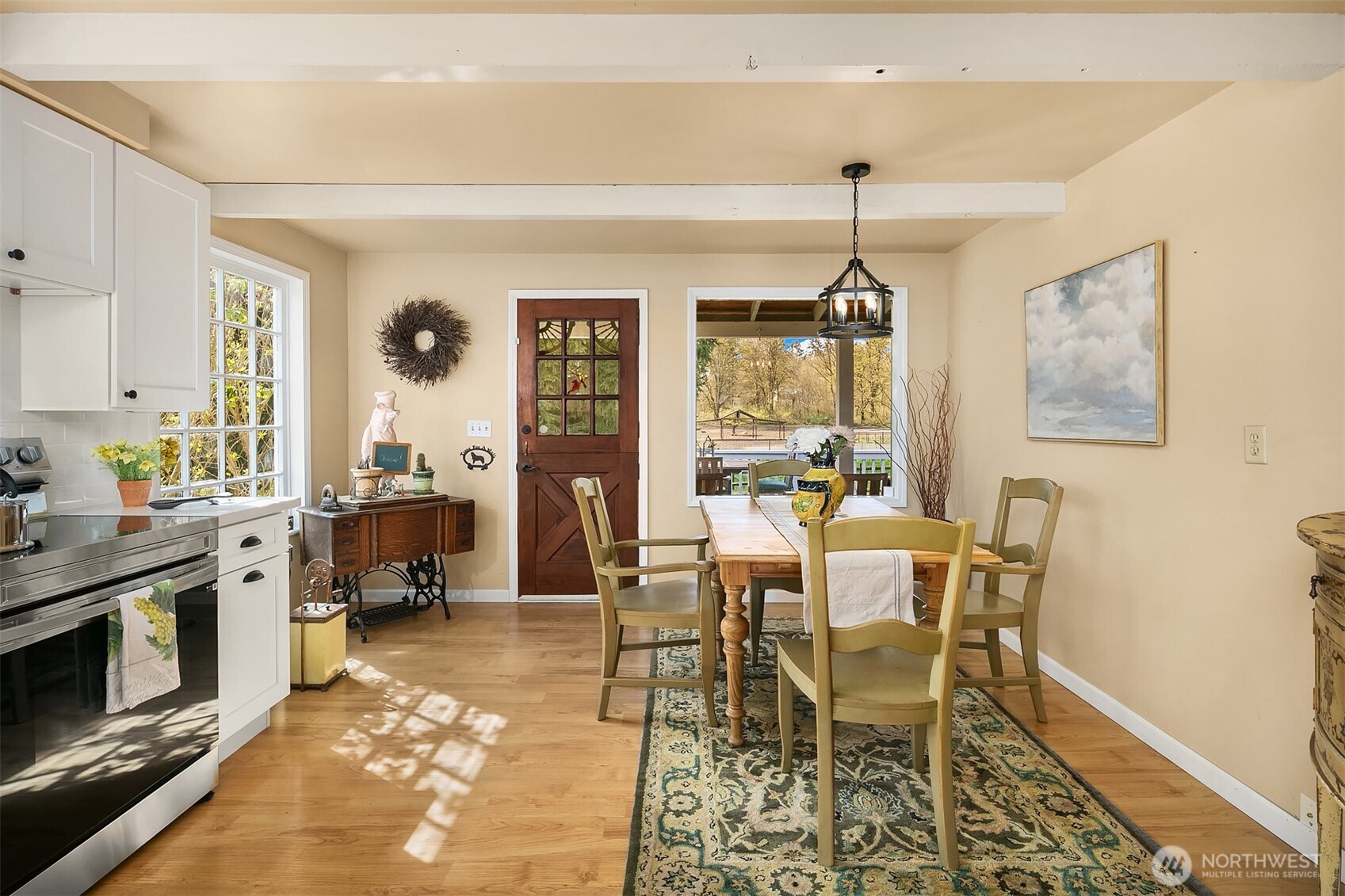Kitchen and dining area with white cabinetry, hardwood floors, and a rustic wooden dining table.