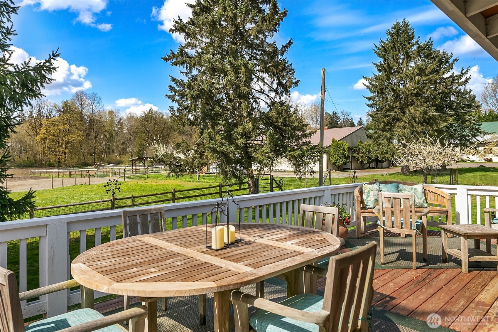 Deck dining area overlooking fenced pasture and mature evergreen trees.
