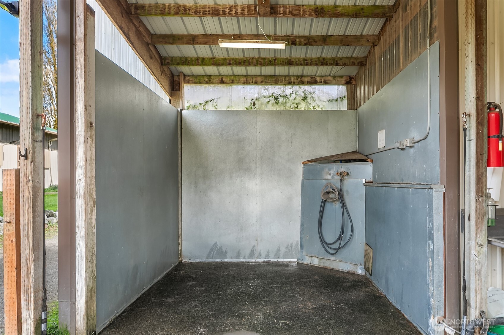 Covered wash bay with a wall-mounted hose and washing equipment.