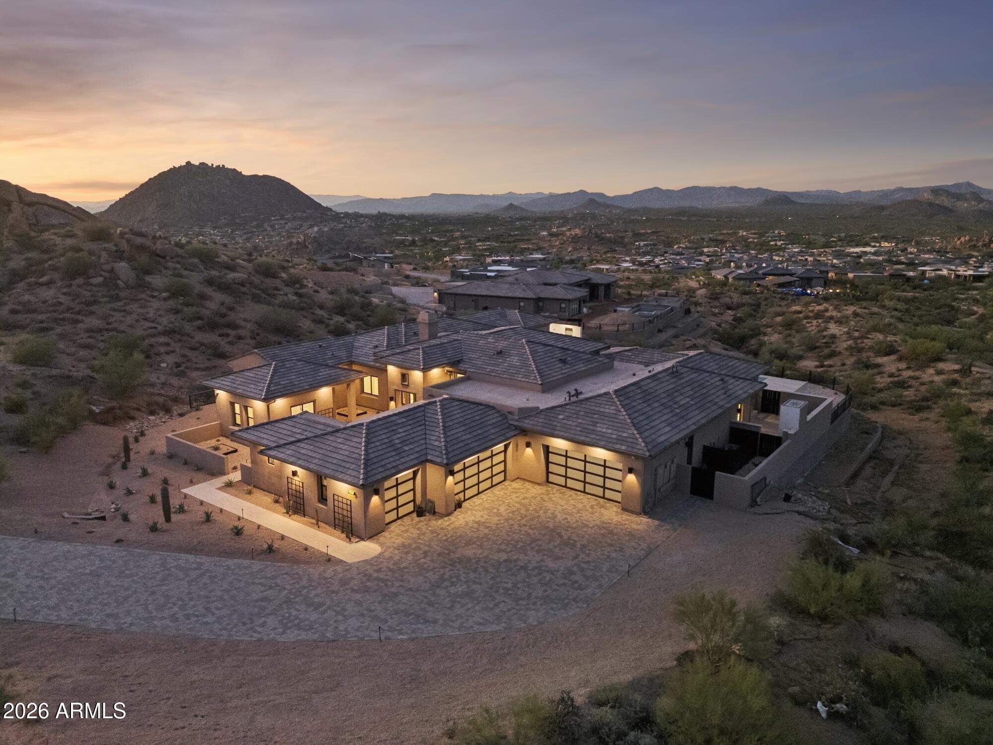 Desert home with tiled roofs and mountain views at dusk.