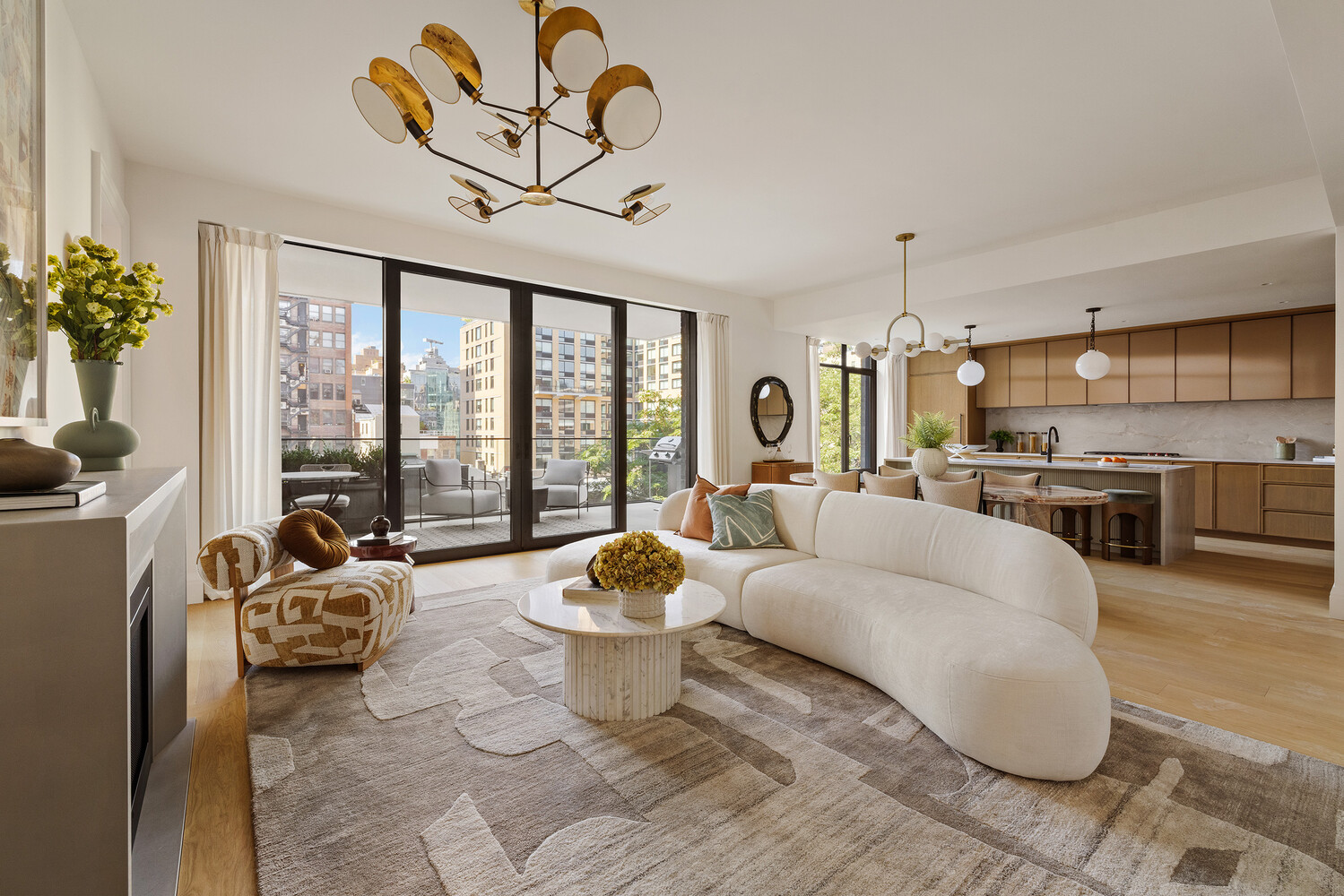 Open-plan living room and kitchen with curved white sofa and floor-to-ceiling windows overlooking the city.