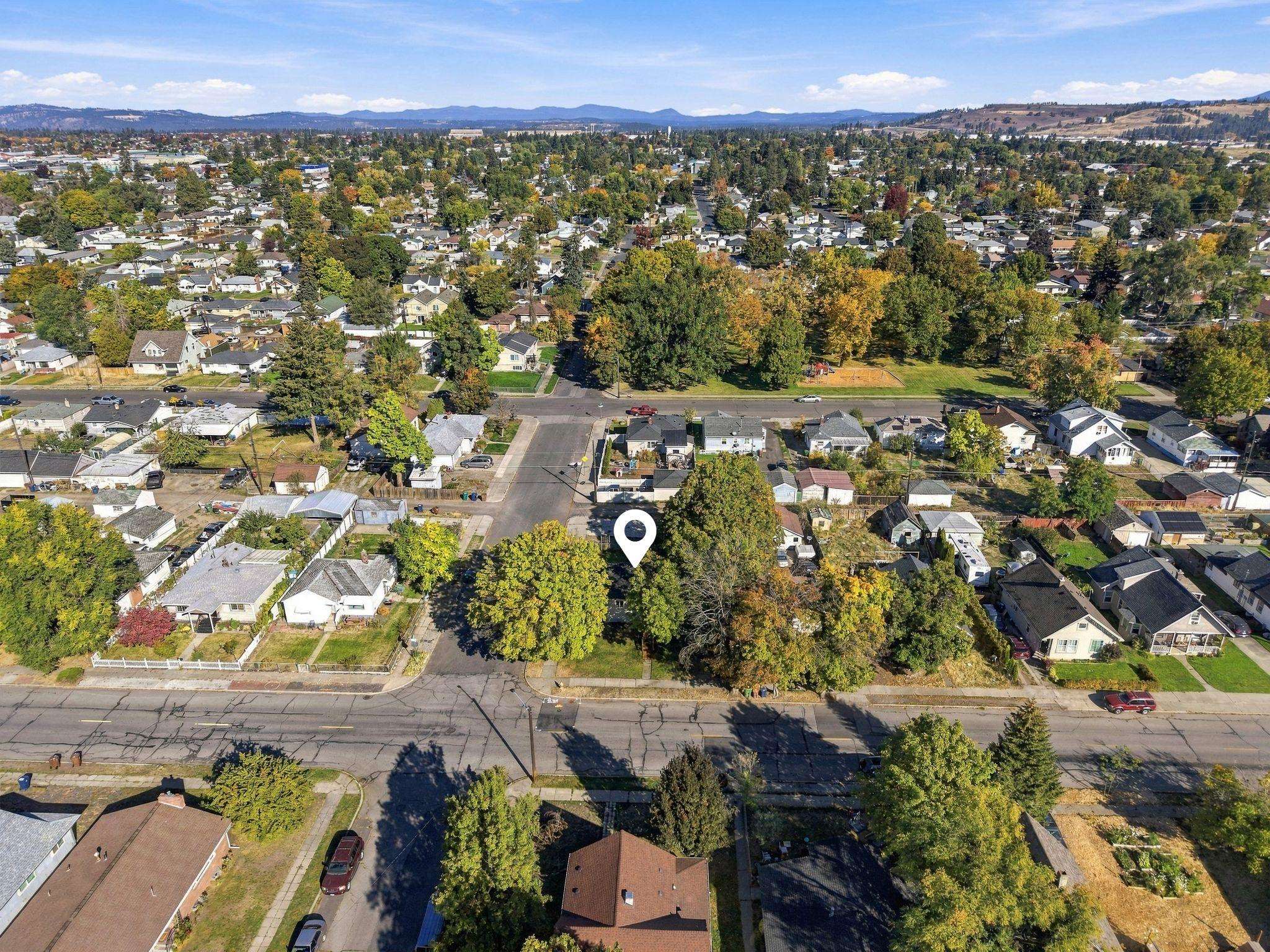 Aerial neighborhood view with a white pin marking the property among tree-lined streets and homes.