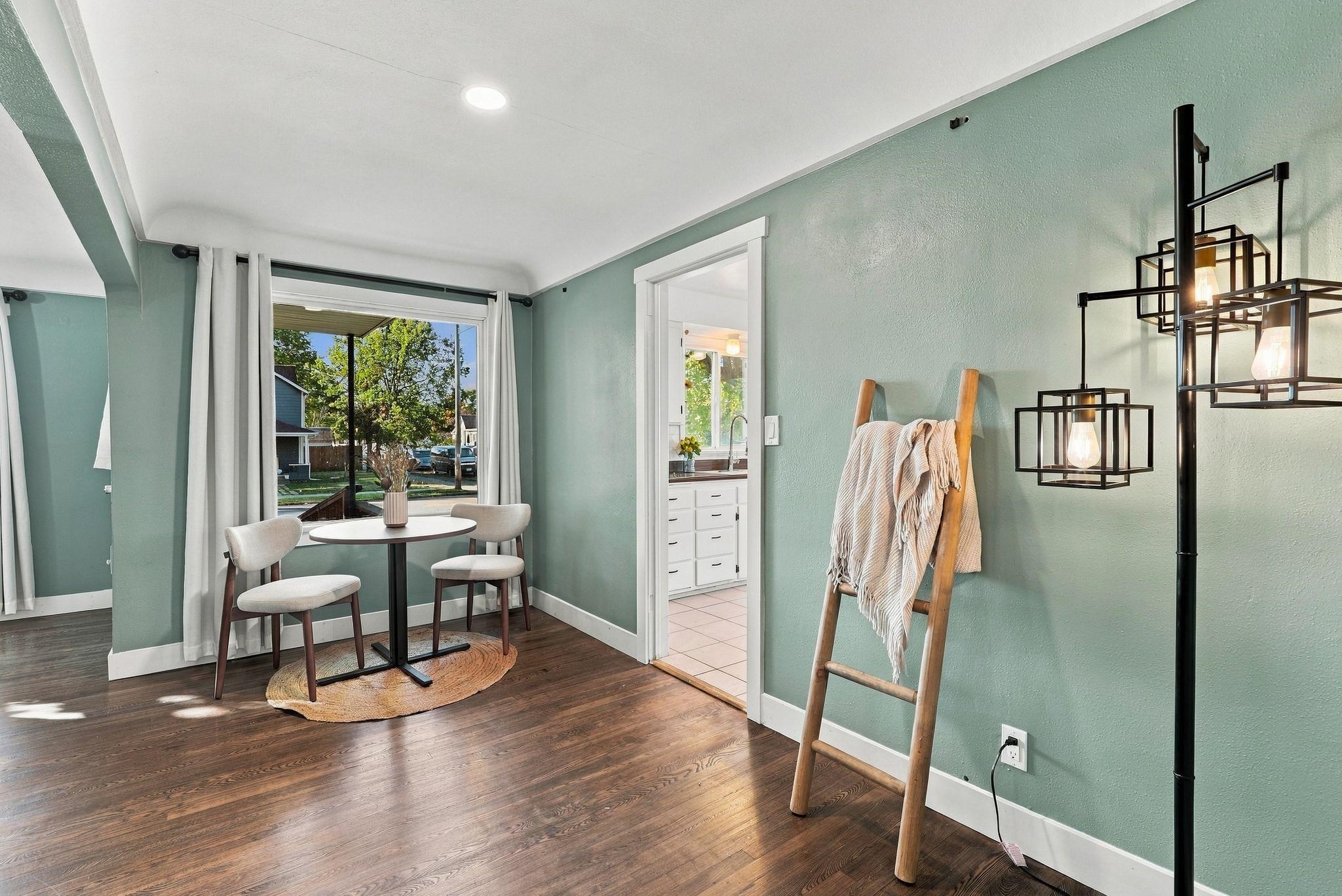 Dining nook with sage-green walls, round table, two chairs, and a window overlooking the yard.