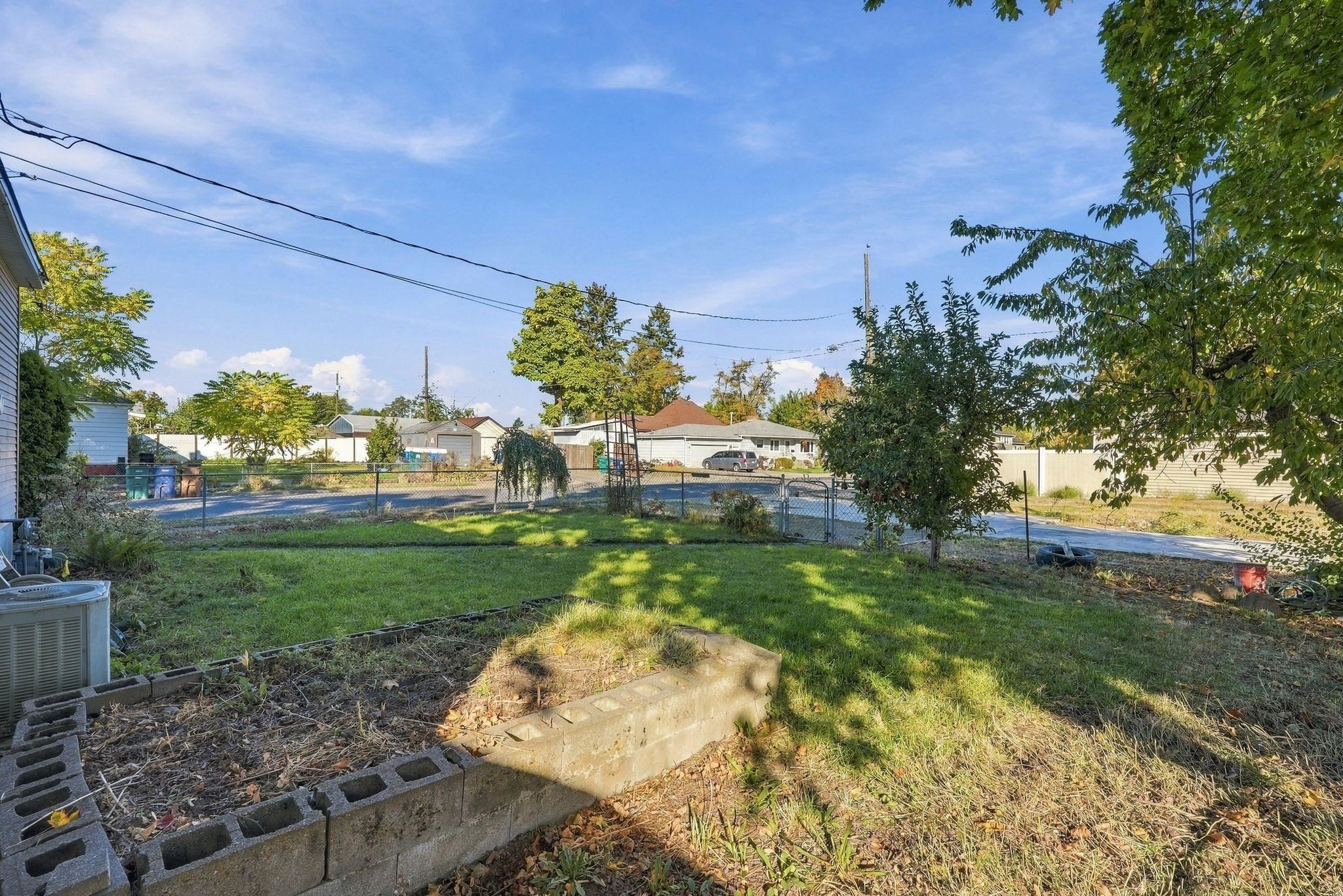 Backyard with a patchy lawn, concrete-block garden bed, and chain-link fence overlooking neighboring homes.