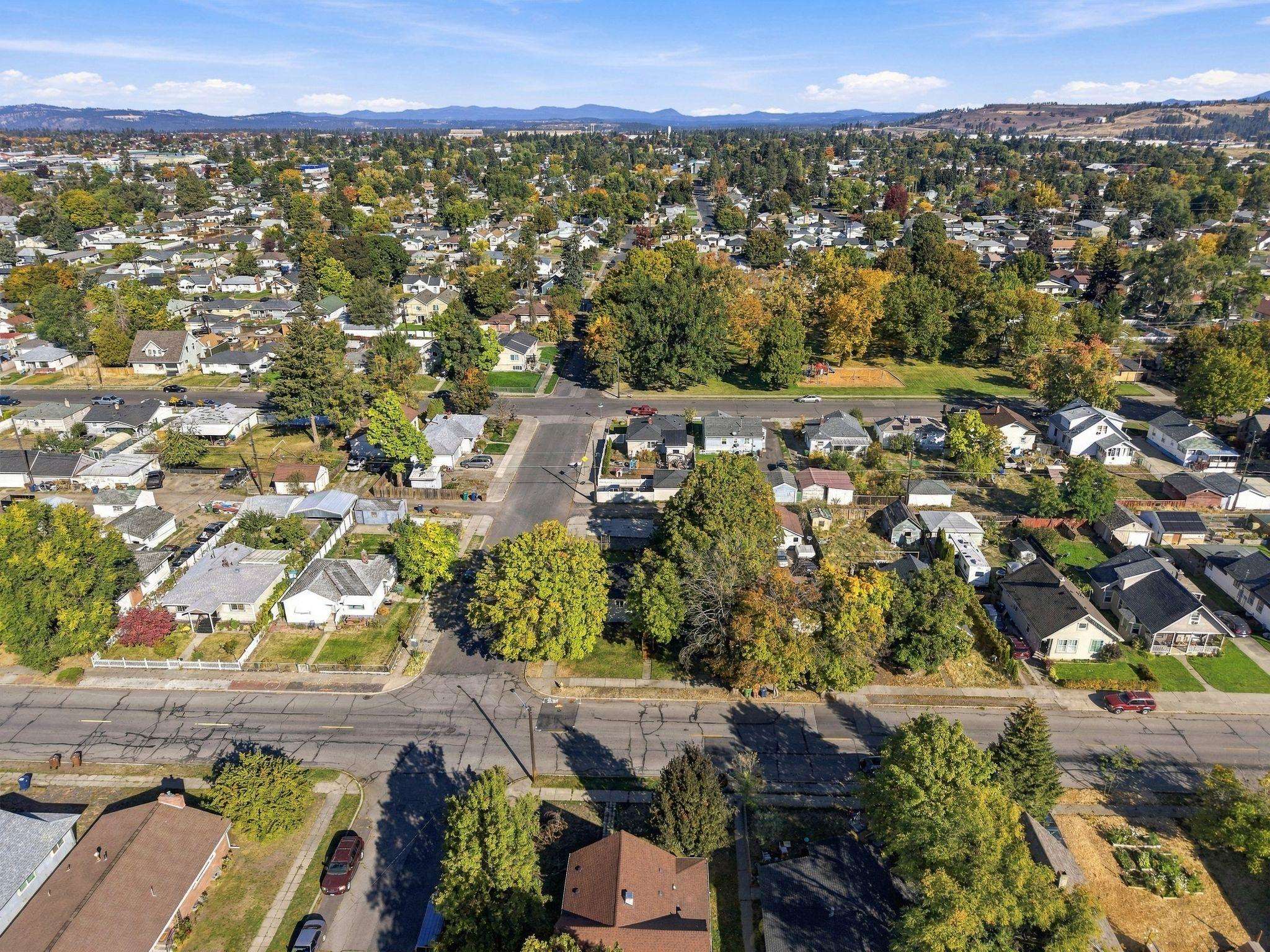 Aerial view of a tree-lined residential neighborhood with autumn foliage and distant hills.