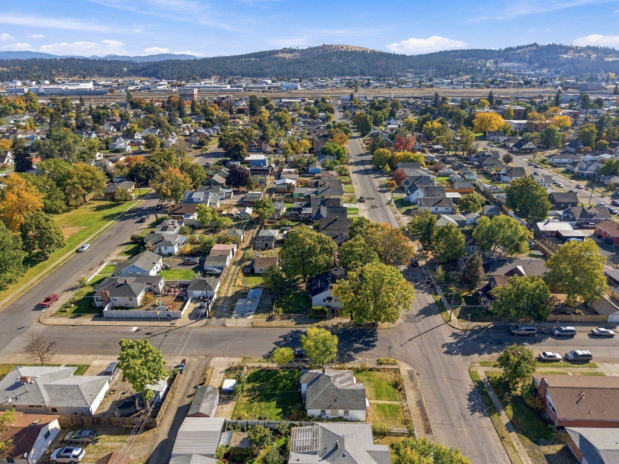 Aerial view of a residential neighborhood with autumn trees and wooded hills in the distance.