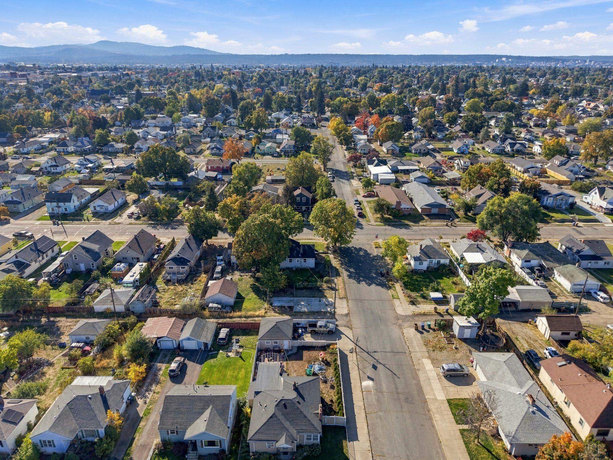 Aerial view of a residential neighborhood with autumn trees and distant hills.