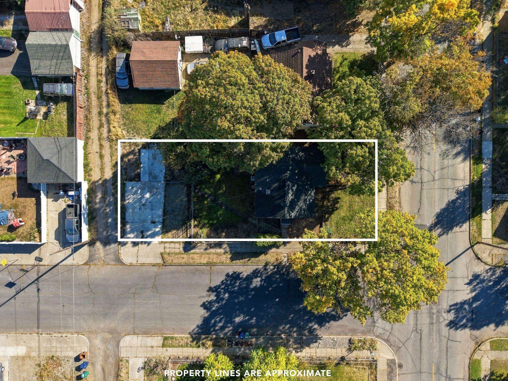 Aerial view of a tree-covered property outlined in white, with the house and street visible.