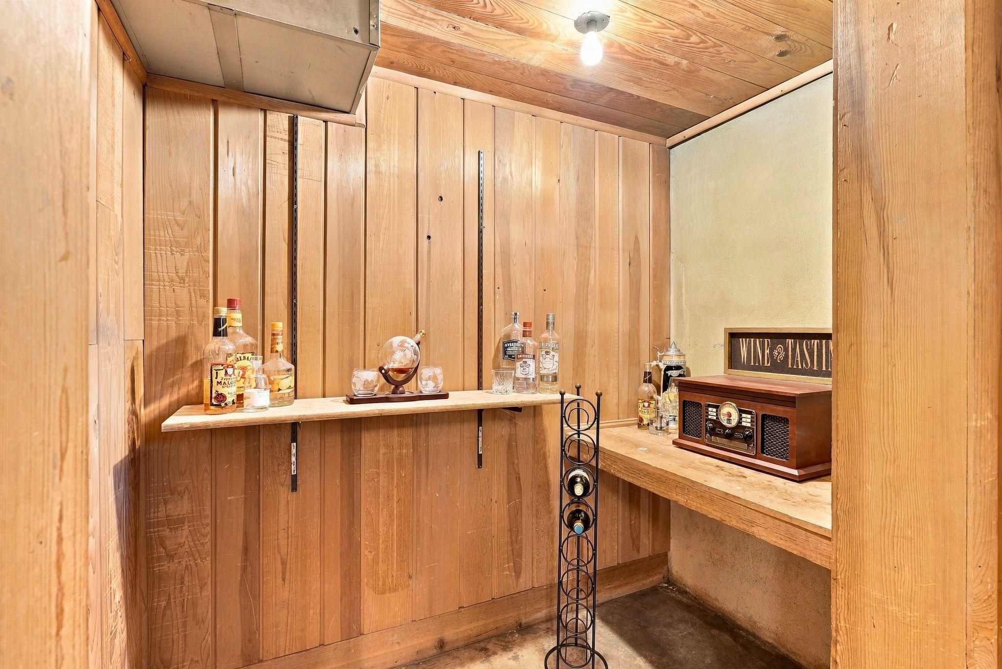 Wood-paneled wine cellar with bottle display, wine rack, and vintage-style radio.