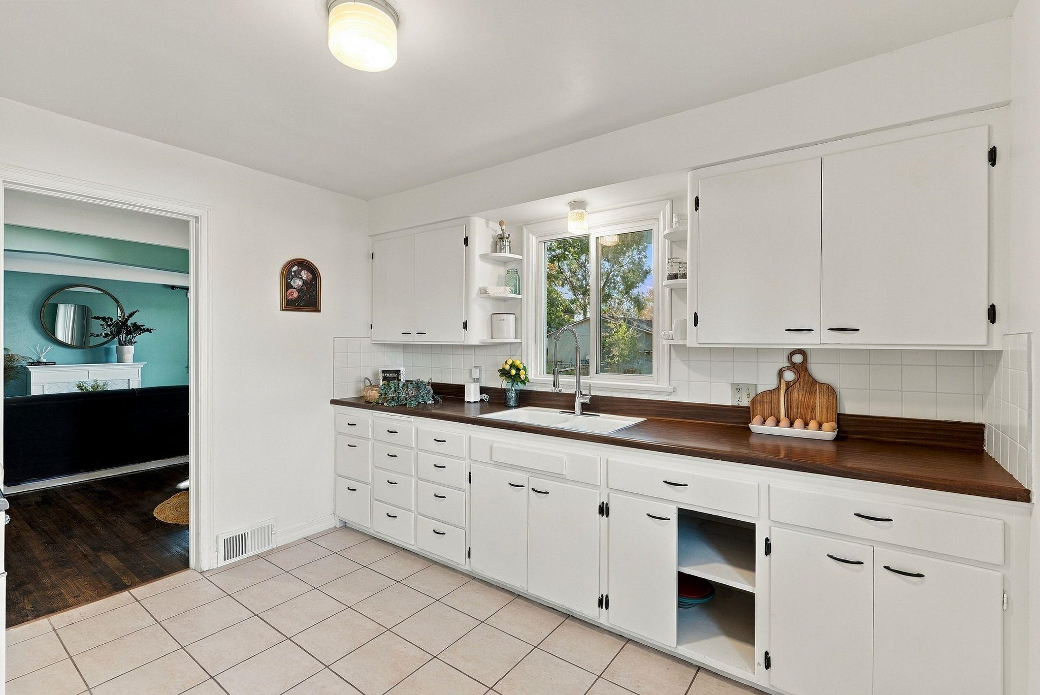Kitchen with white cabinets, dark wood countertops, and a sink beneath a window.