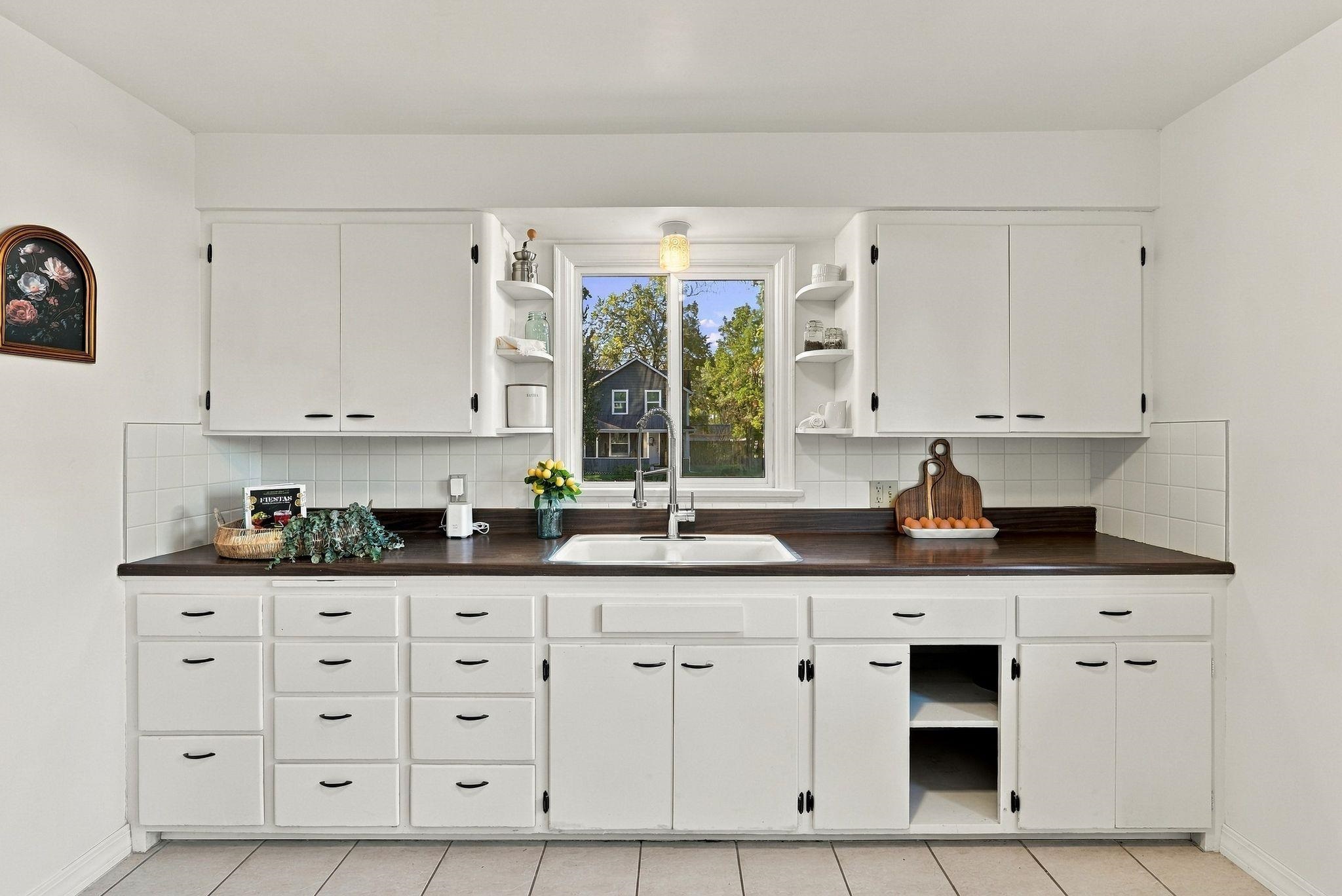 Kitchen with white cabinets, dark countertops, and a sink beneath a window.