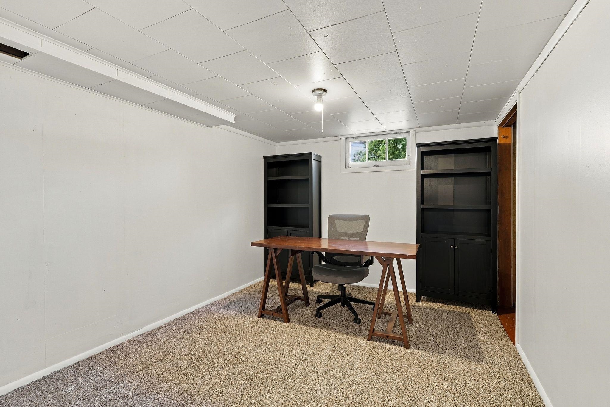 Home office with a wooden desk, rolling chair, and two black bookcases