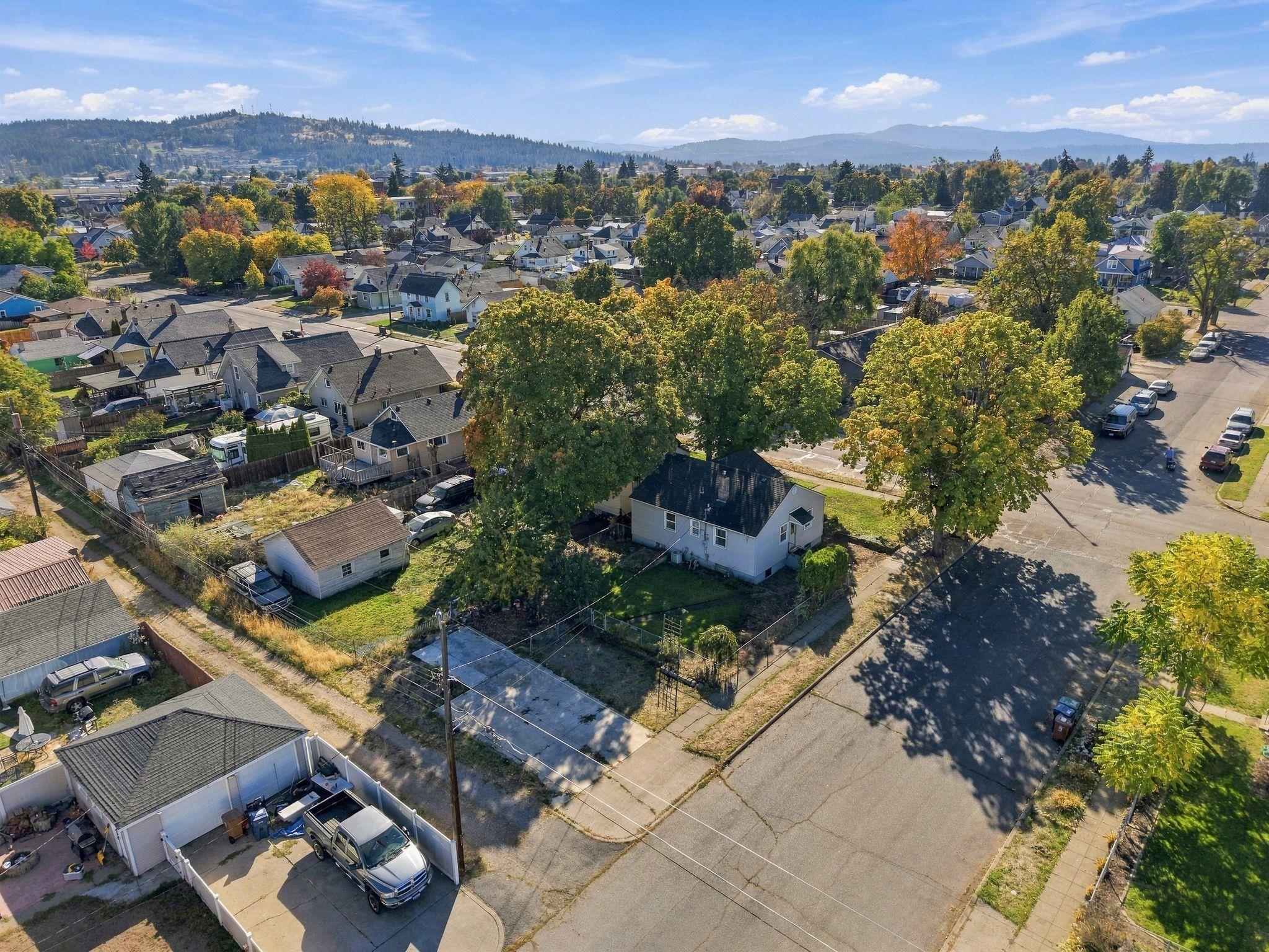 Aerial view of a Spokane home amid autumn trees, nearby homes, and distant hills.