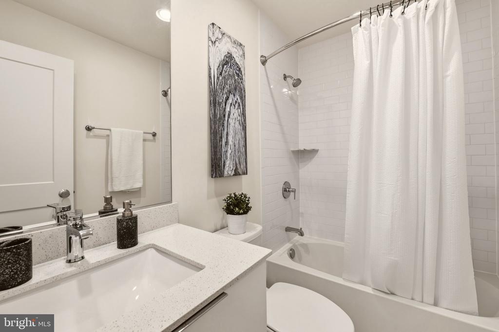 Bathroom with a white vanity and bathtub behind a shower curtain.