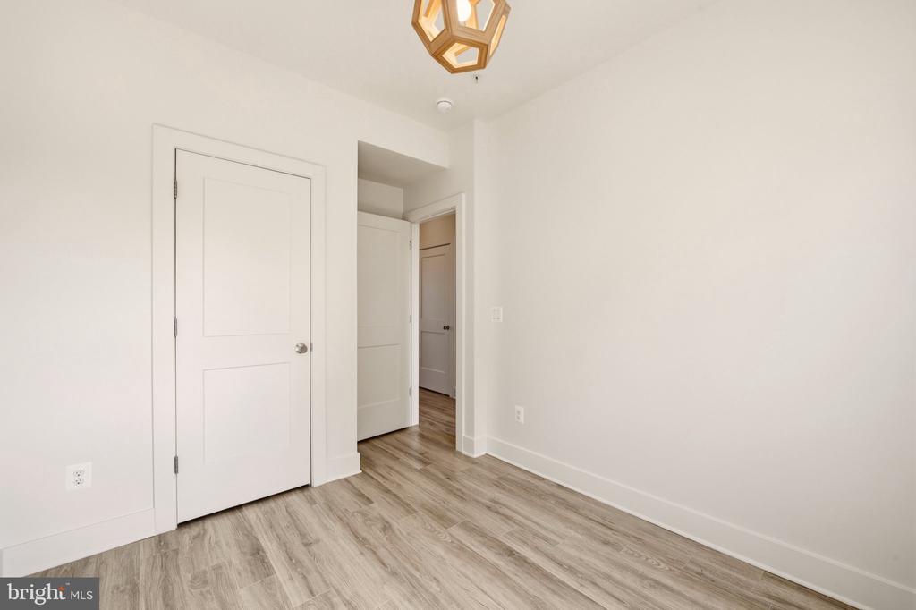 Empty room with gray wood-look flooring, white walls, and a geometric ceiling light.