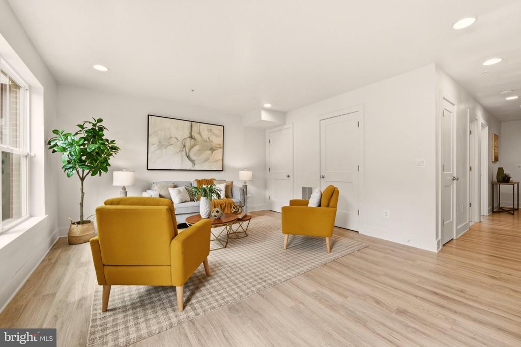 Staged living room with mustard-yellow armchairs, a light sofa, and large windows.