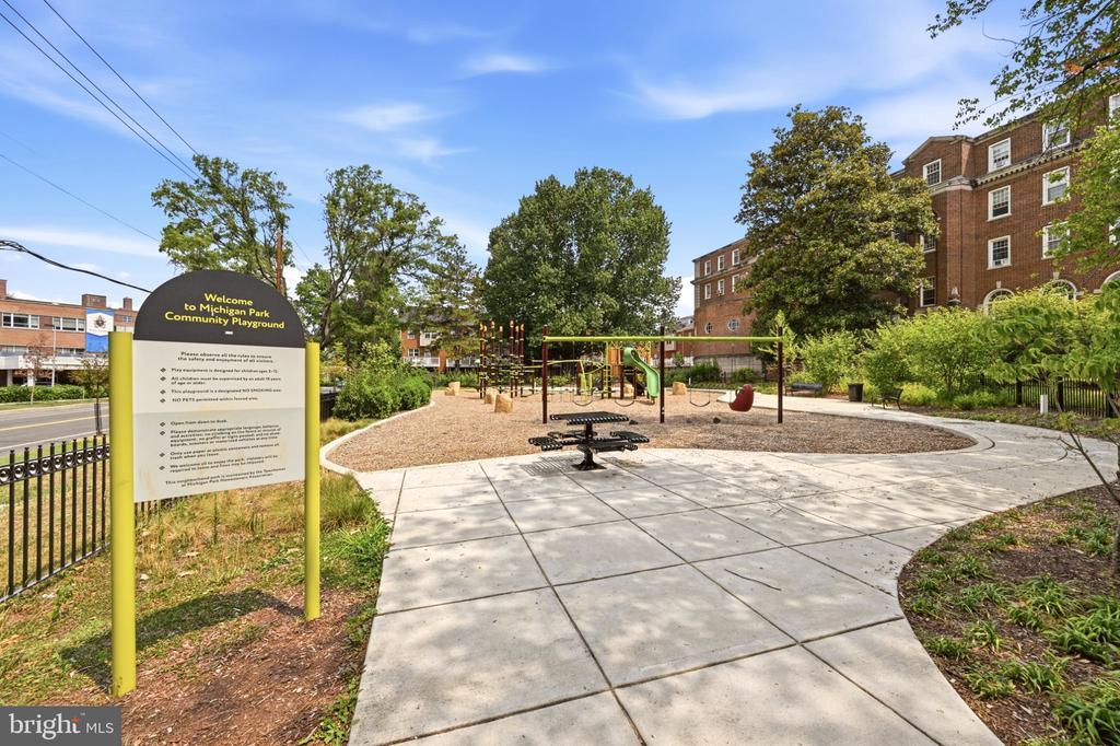 Michigan Park Community Playground with swings, climbing equipment, and a paved path.