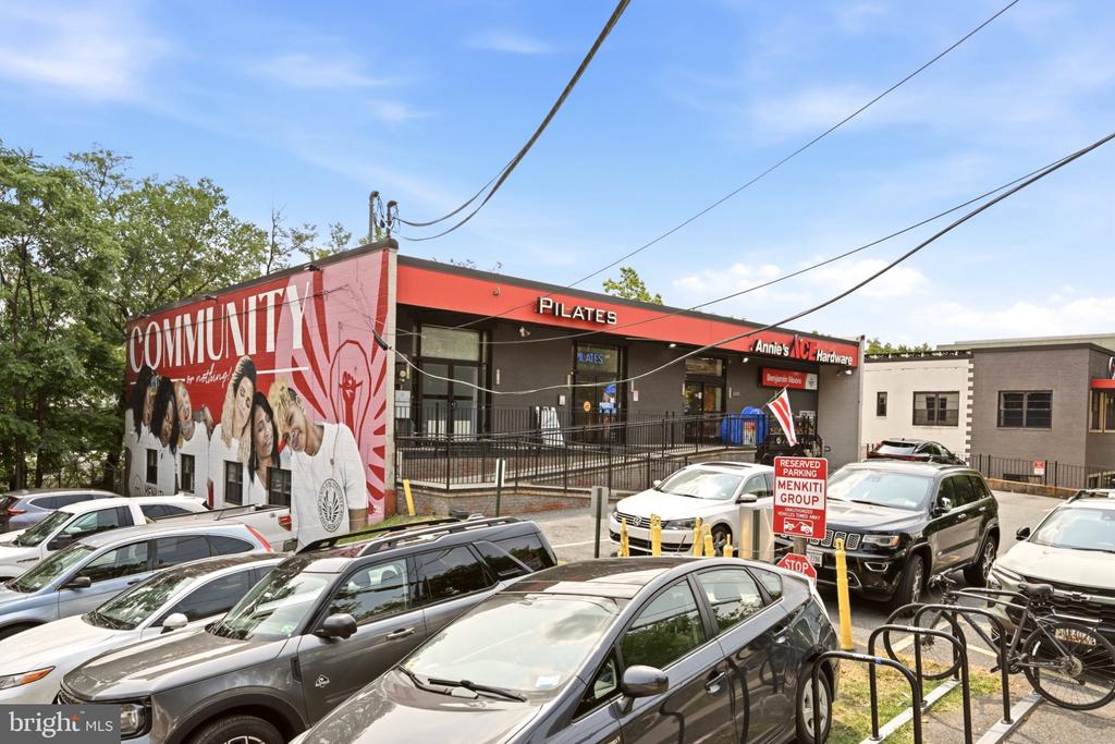 Neighborhood storefronts with a large COMMUNITY mural and a crowded parking lot.