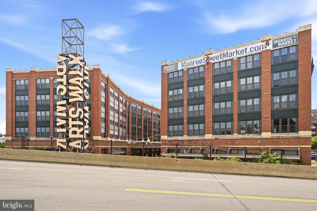 Multi-story brick Monroe Street Market building with a prominent vertical Arts Walk sign.