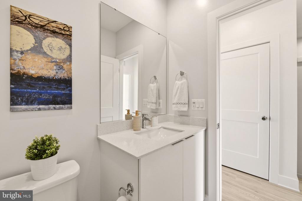 Bright bathroom with a white vanity, large mirror, and abstract wall art.