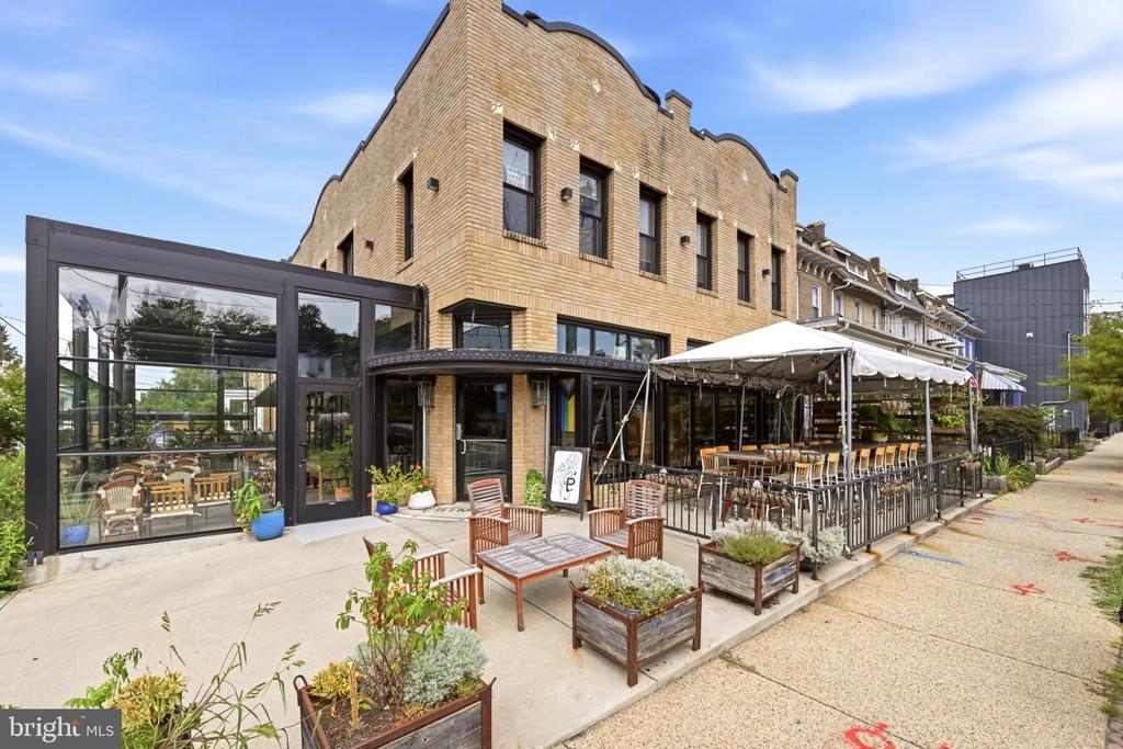 Brick commercial building with a glass storefront and outdoor dining patio.