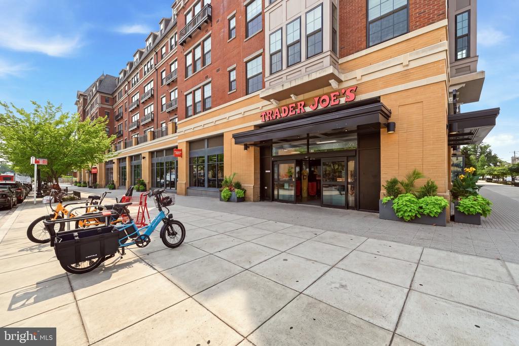 Mixed-use brick building with a Trader Joe’s storefront and cargo bicycles on the sidewalk.