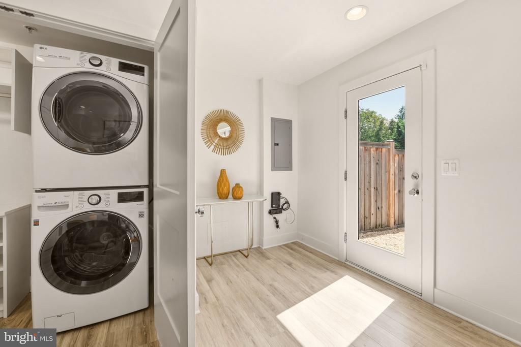 Laundry and entry area with stacked washer and dryer, slim console, and glass back door.