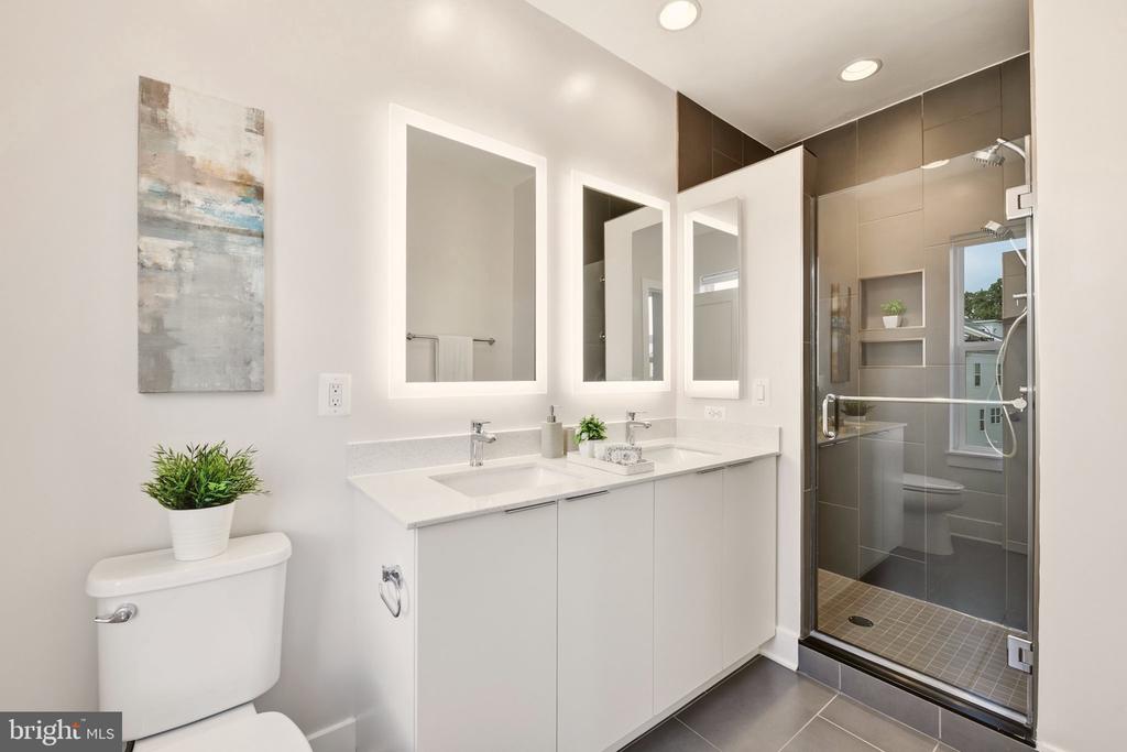 Modern bathroom with a white double vanity and glass-enclosed tiled shower.