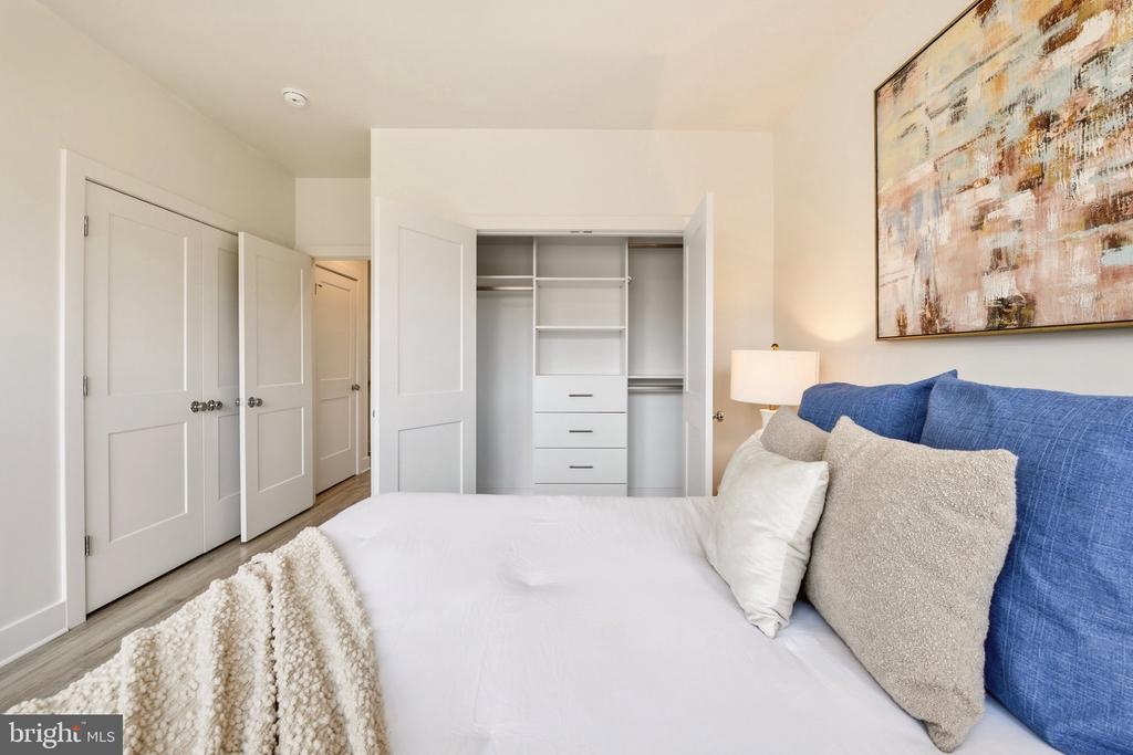 Bedroom with a white bed, blue pillows, and an open built-in closet.