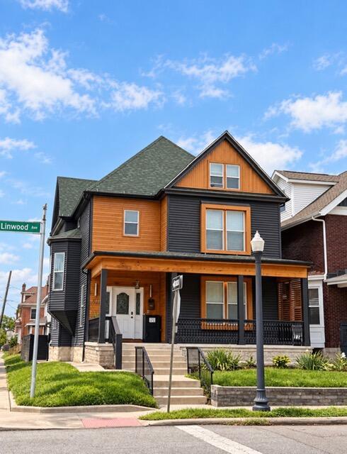 Two-story orange-and-charcoal house with a covered porch on a landscaped corner lot.