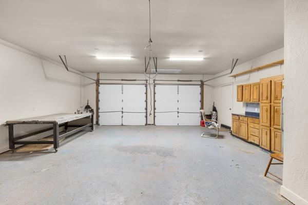 Two-car garage with wooden storage cabinets, a workbench, and two overhead doors.