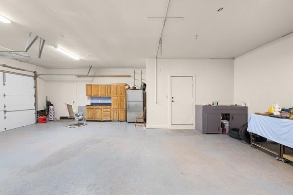 Spacious garage with wooden storage cabinets, a white overhead door, and a workbench.