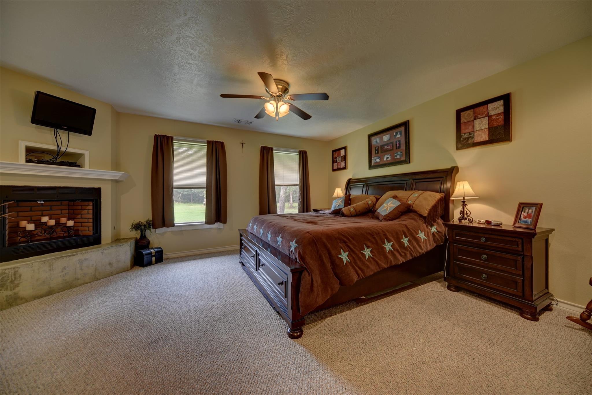 Bedroom with a large dark wood bed, star-patterned bedding, and a brick fireplace.