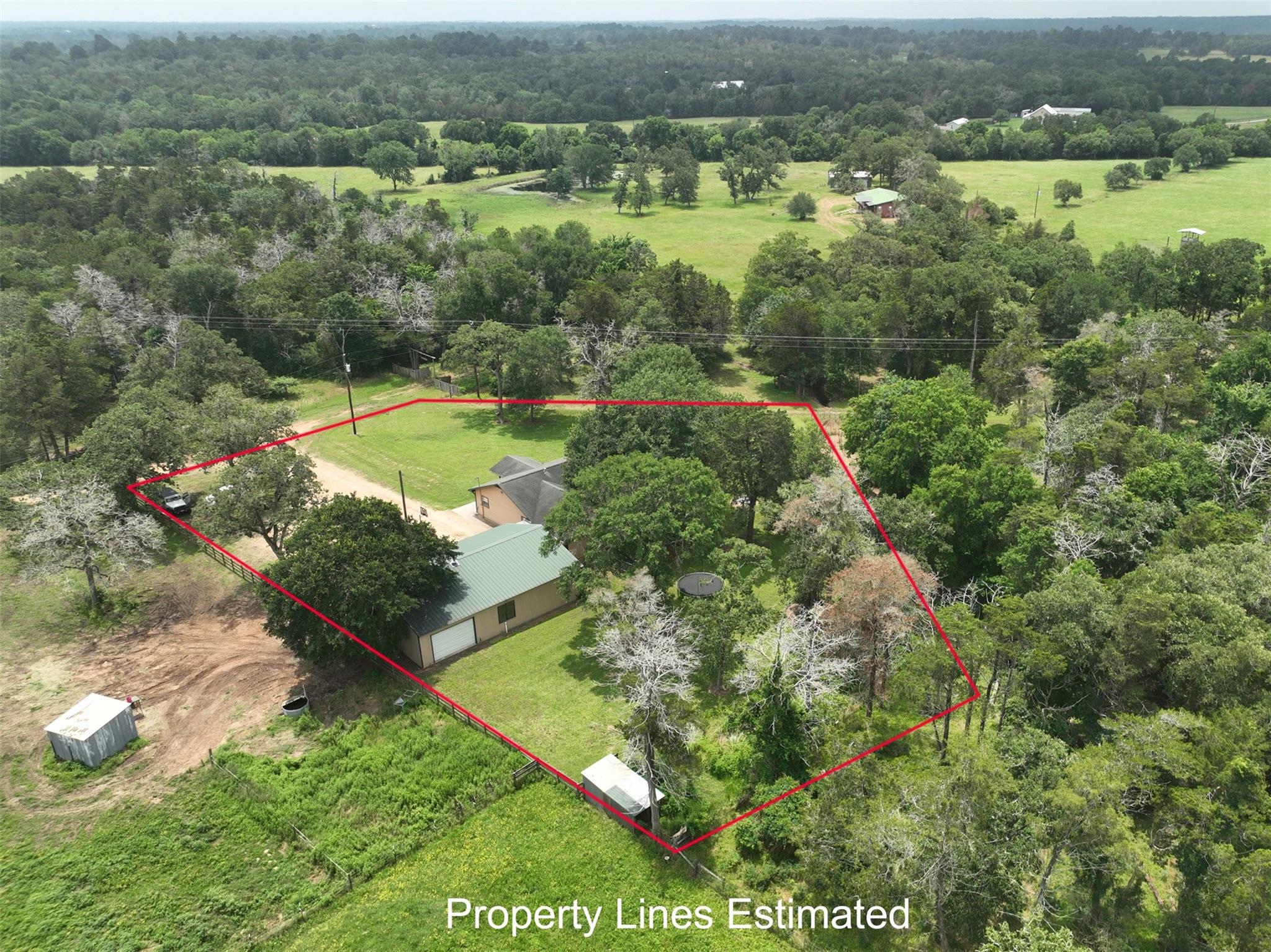 Aerial view of a tree-shaded rural property outlined with estimated red boundary lines.