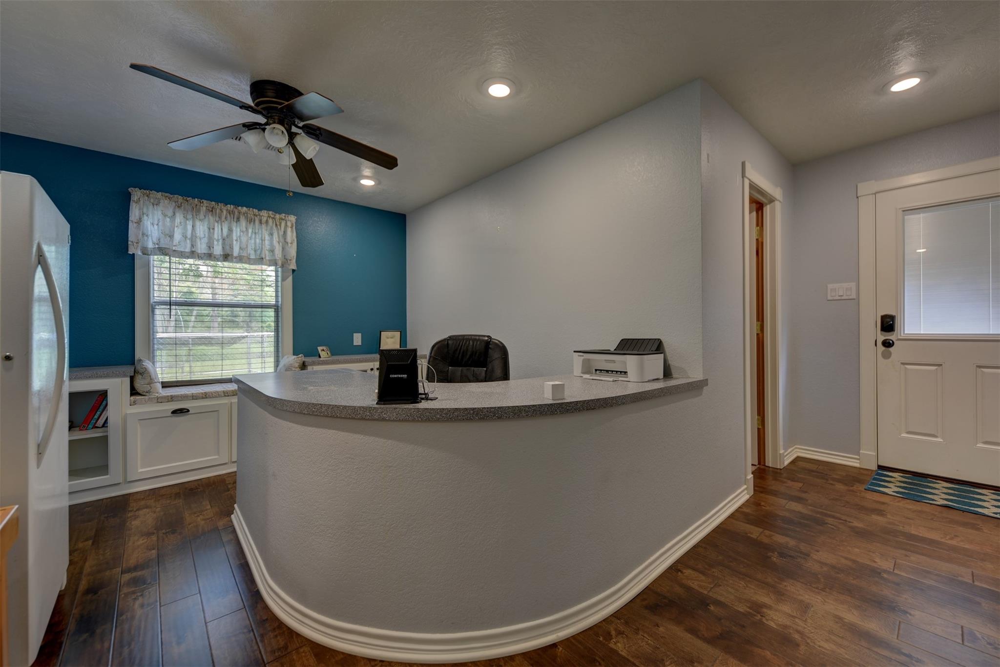 Office reception area with curved counter, teal accent wall, and built-in window seat.