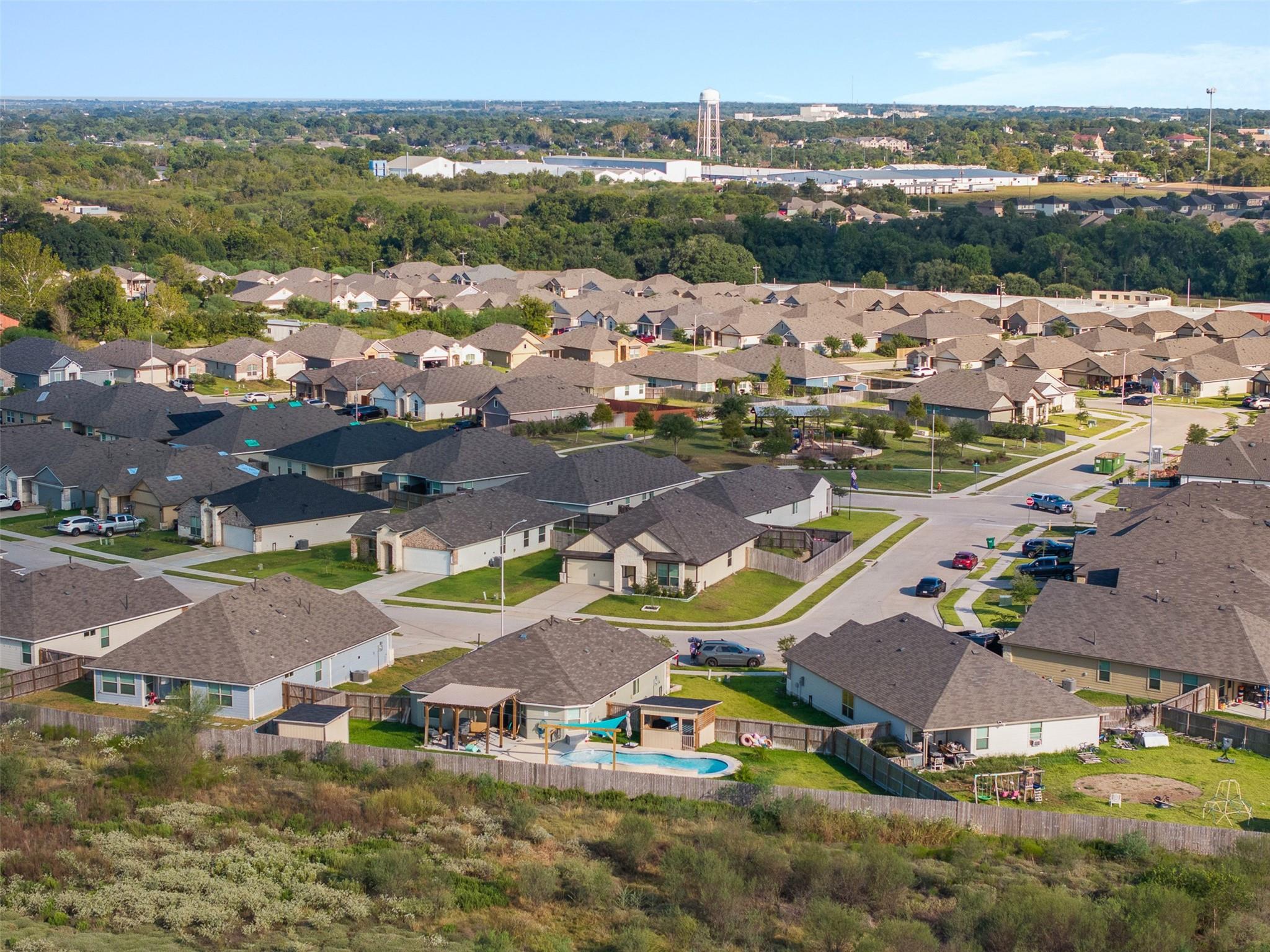 Aerial view of a residential neighborhood with a backyard pool and distant water tower.