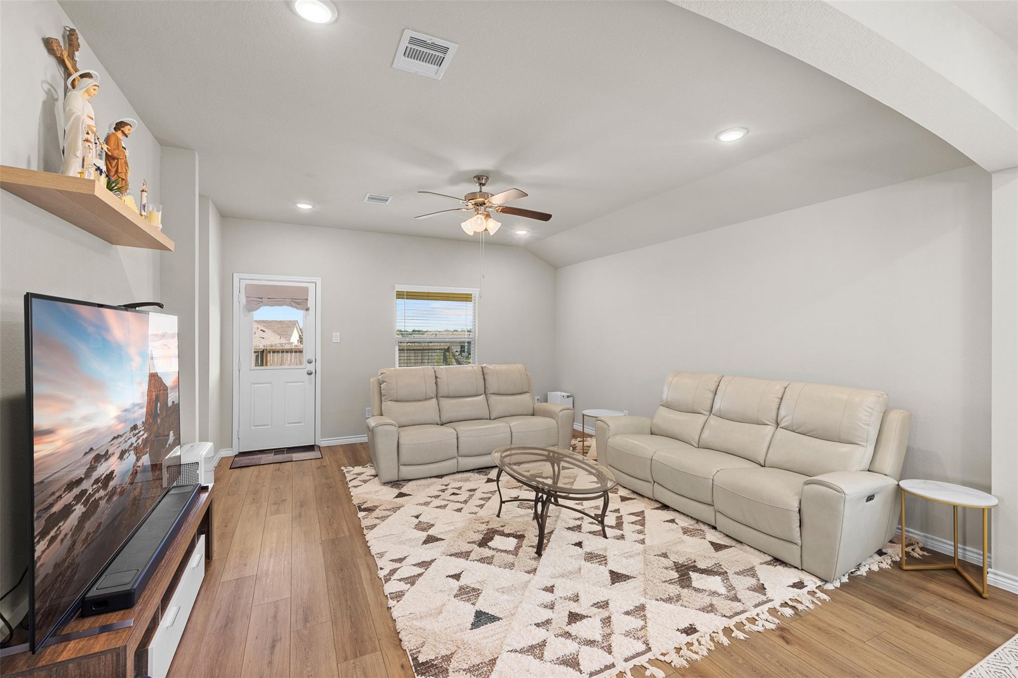 Living room with cream sofas, a geometric rug, and a large television.